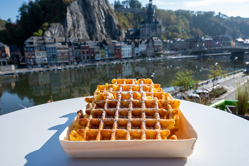 Sweet fresh baked Belgian waffles served outdoor with view on Maas river in Dinant, Wallonia, Belgium close up
