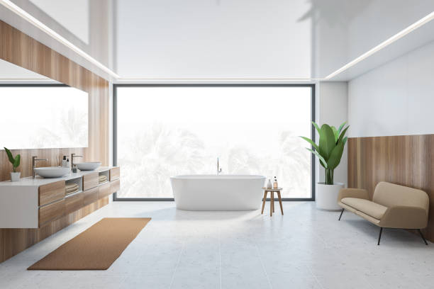 istock Wooden and white bathroom with white bathtub, sofa and window 1307094775