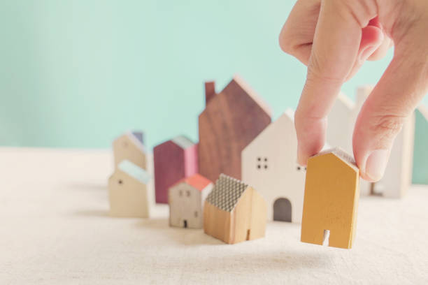 escolha manualmente casa em miniatura amarela, procurando propriedade certa em boom habitacional de alta demanda, tomando decisão sobre o conceito de investimento residencial - dificuldade de habitação - fotografias e filmes do acervo