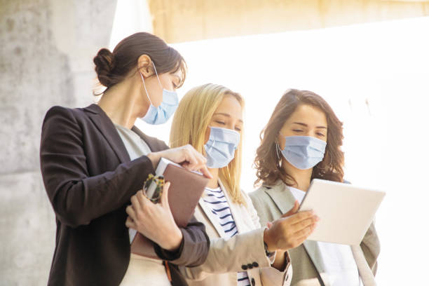 istock Three female university students wearing protective mask sharing information on tablet 1307098185