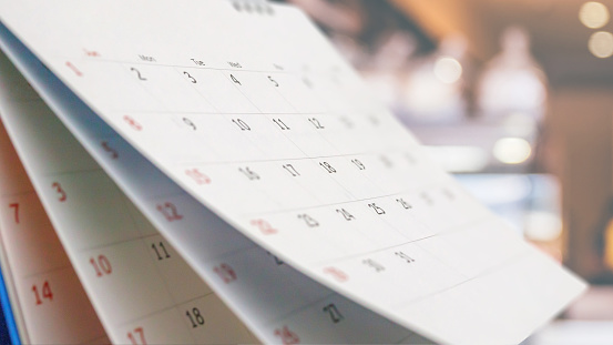 Cierre el calendario del escritorio de papel blanco con una cita de fondo borrosa y un concepto de reunión de negocios photo