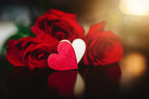 Composition for Valentine's Day with a gift box and a bouquet of roses on a blurred background with bokeh lights.