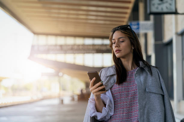 istock Young woman waiting on station and using smart phone 1307100028