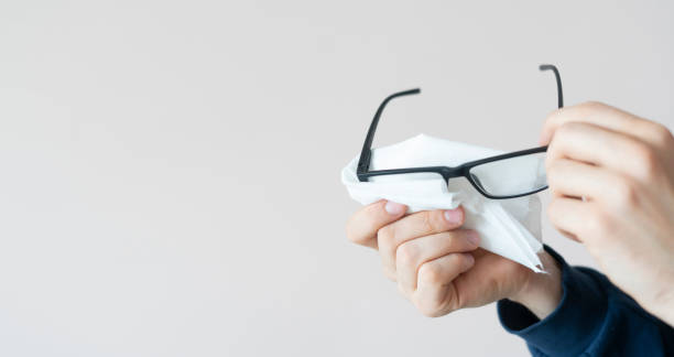 istock person's hands holding eye glasses and wipe the lenses, clean view sight 1307110254
