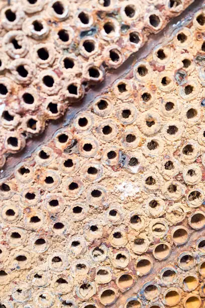 Photo of Selective focus tube sheet or plate of heat exchanger or boiler closeup texture macro diagonal background full of hard insoluble mineral deposits salts scale and corrosion. Trypophobia concept.