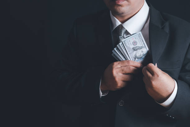 Man putting bribe money into pocket on black background, Man putting bribe money into pocket on black background, Concept for corruption, finance profit, bail and crime politician stock pictures, royalty-free photos & images