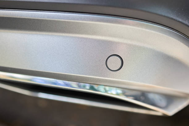 istock Selective focus on bumper right side parking sensor at back of luxurious car bumper close up on light blurred with sun flare background with copyspace. 1307120065