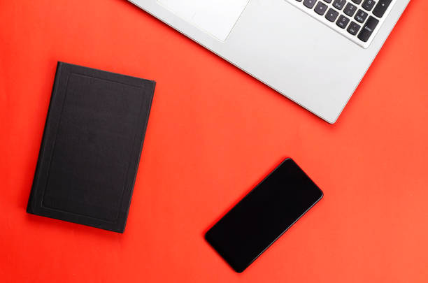 istock Hardcover book, phone, laptop on a red background. 1307125370