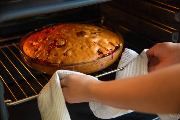 the girl's hands hold a hot baking dish with a cake, towel, kitchen, oven