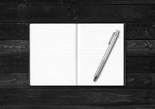 Blank open notebook and pen mockup isolated on black wood background