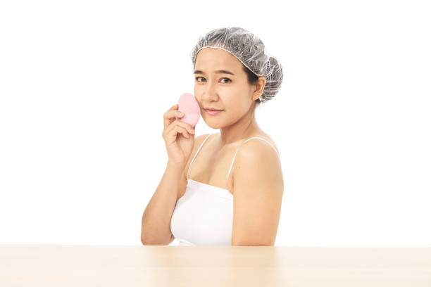 attraente e bella giovane donna lavaggio viso con pennello e schiuma detergente su sfondo bianco. prodotti cosmetici - scrub brush immagine foto e immagini stock
