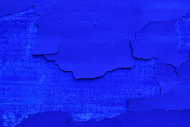 Extreme close-up of paint peeling off on blue painted canvas.