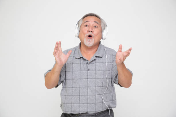 hombre asiático senior escuchando música con auriculares y bailando aislado sobre fondo blanco - samba dancing audio fotografías e imágenes de stock