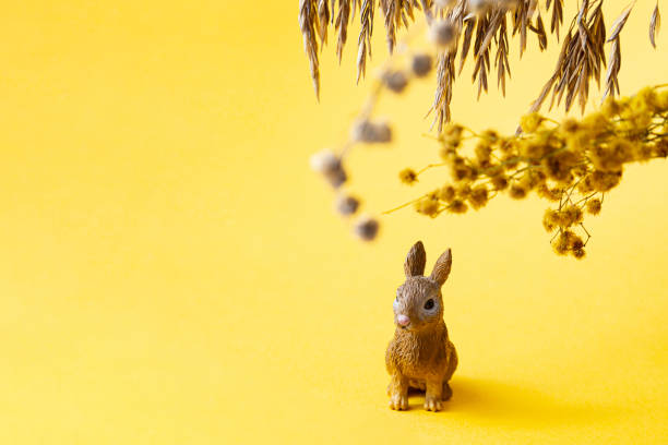 istock Easter bunny and dried flowers on a yellow background. Modern easter concept, copy space, selective focus. Minimal creative postcard layout. 1307141330