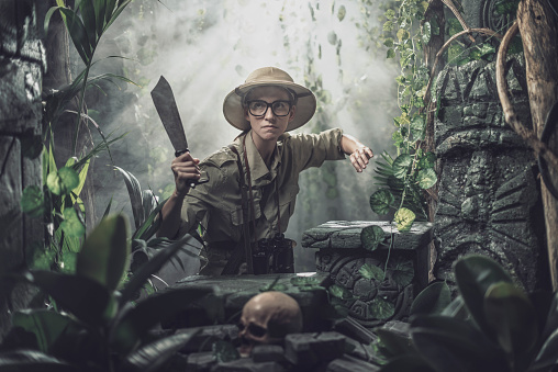 Vintage adventurer exploring the jungle and holding a machete, she finds ancient ruins