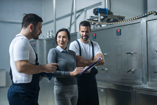 istock Blue collar workers and their female manager working on reports in a factory. 1307142244