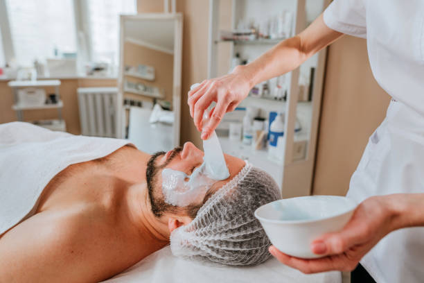 istock Esthetician making facial cleansing procedure using algae mask for a man 1307143965