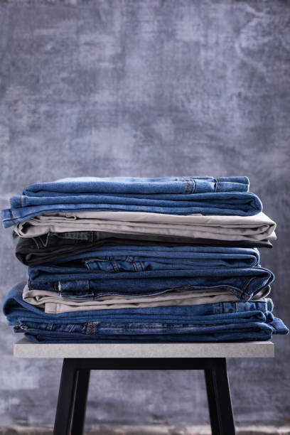 istock Stack of denim blue jeans near old wall background texture 1307147267