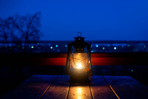 istock Relaxing background with ancient kerosene lamp on the table against the landscape with bokeh. 1307147330