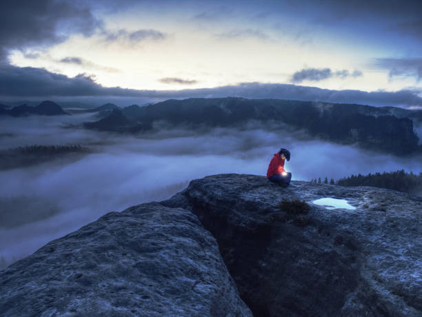 la donna nelle mani tiene il sole. la ragazza dell'escursionista si siede nella notte buia sopra le nuvole e aspetta l'alba. - mountain climbing flash foto e immagini stock