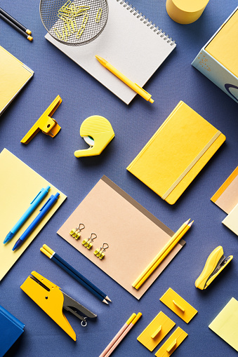 From above of assorted colorful office and school stationery placed on blue background