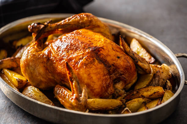 istock Whole baked golden crispy chicken in a pan cooked with potatoes 1307152481