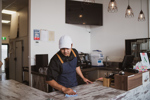 The portrait of the owner of small businessman disinfecting the table.