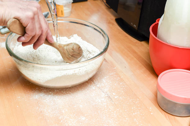 istock Person making bread in home kitchen adding ingredients to make the dough 1307154691