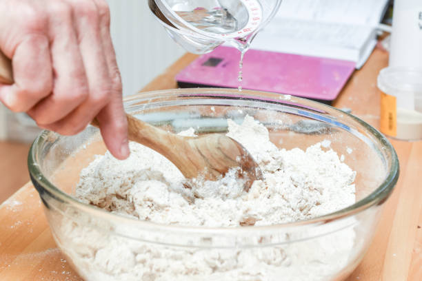 istock Person making bread in home kitchen adding ingredients to make the dough 1307155266