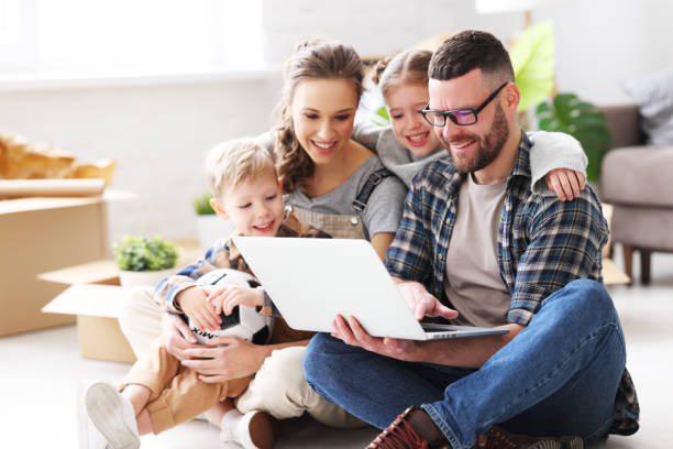 genitori e bambini sorridenti che navigano laptop in un nuovo appartamento - 16377 foto e immagini stock