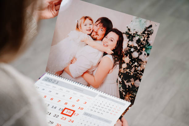 A woman looks at a calendar with a family photo. A woman looks at a calendar with a family photo. A useful gift with your photos. Souvenir. additional photographer's service. convenience photos stock pictures, royalty-free photos & images
