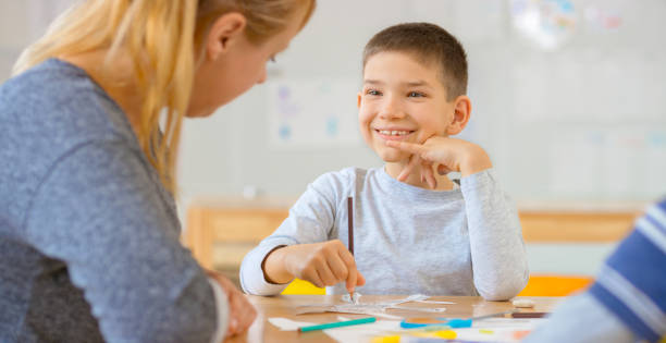 istock Smiling boy looking at teacher 1307158967
