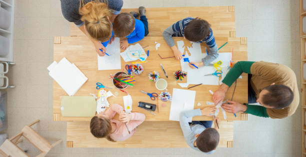 istock Overhead view of teachers helping children making puppets 1307158991