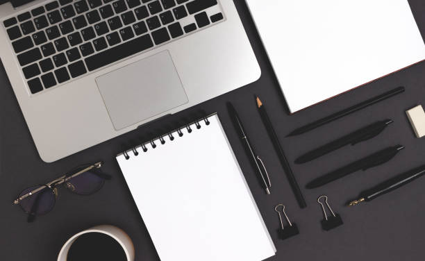 istock Laptop and office supplies on a black background. 1307159140