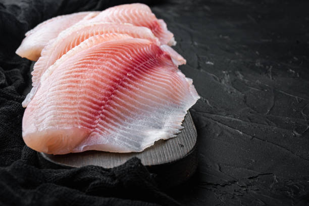 istock Tilapia fish skinless meat, on black background 1307160262