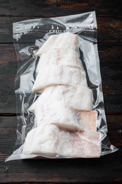 istock Raw haddock fish skinless, plastic vacuum packaged, on dark wooden background 1307160368