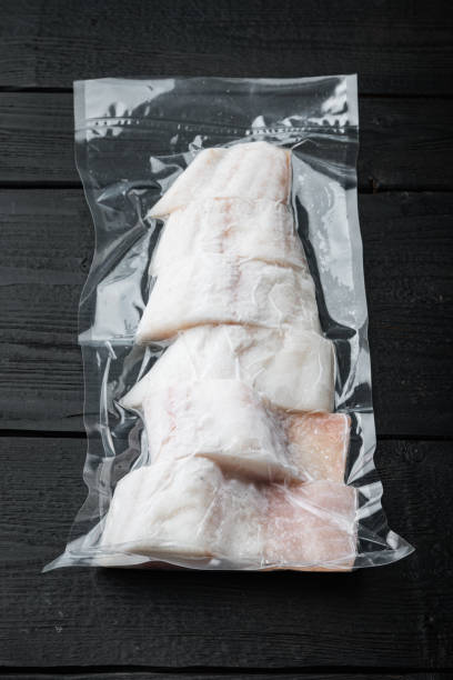 istock Raw haddock fish skinless, plastic vacuum packaged, on black wooden table 1307160518