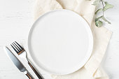 An empty plate and cutlery on a white table.