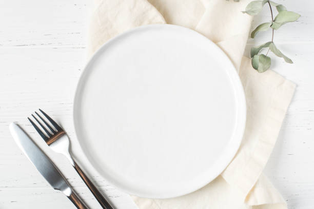 an empty plate and cutlery on a white table. - pôr a mesa imagens e fotografias de stock