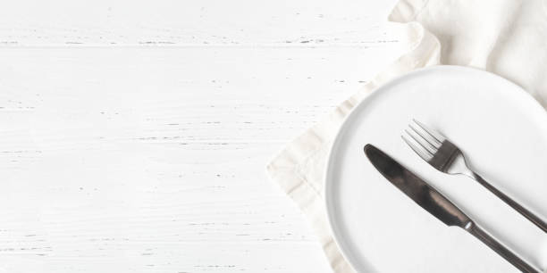 istock An empty plate and cutlery on a white table. 1307161315