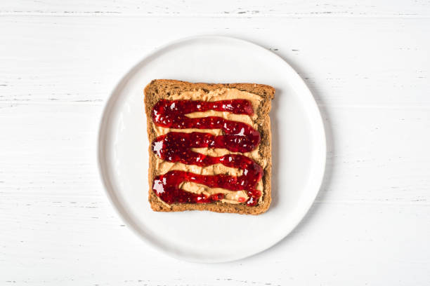 Homemade peanut butter sandwich with raspberry jam. Homemade peanut butter sandwich with raspberry jam on wooden background. raspberry jam stock pictures, royalty-free photos & images