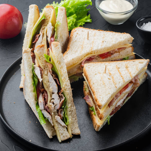istock Club sandwich with meat, cheese, tomato, ham, on black background 1307162014