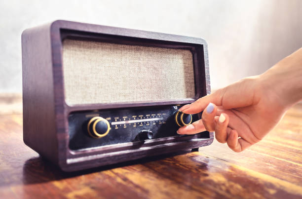 sintonizzazione radio retrò. donna che usa vecchie attrezzature di musica vintage. regolazione della manopola del sintonizzatore di volume o frequenza. accensione o spegnimento del ricevitore stereo o dell'altoparlante. - radio foto e immagini stock