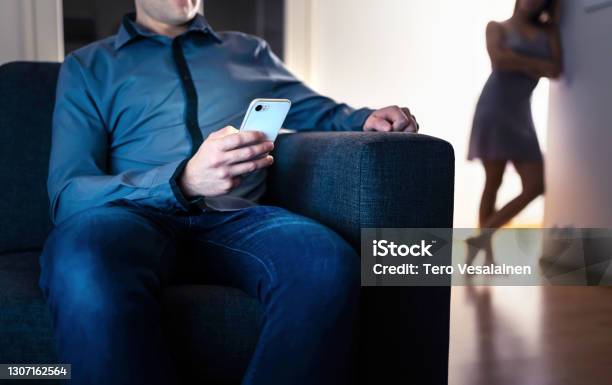 Jealous Woman And Cheating Man With A Phone Infidelity Jealousy And Betrayal Cheater Husband Texting With Mistress And Secret Lover Suspicious Wife Peeking And Spying Stock Photo - Download Image Now