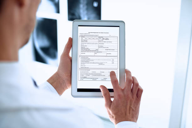 doctor is using a digital tablet to fill out the registration form stock photo