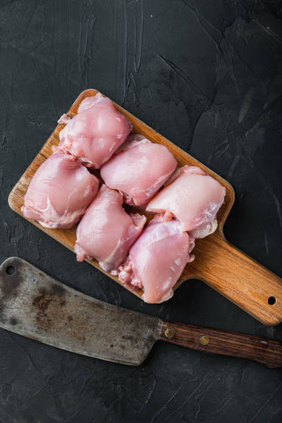 istock Organic chicken thighs with meat cleaver, on black background, top view with space for text, flat lay with copy space 1307162901