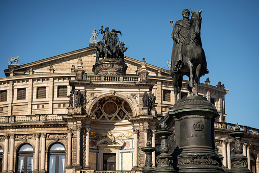 Dresden, Germany - March 02, 2021: View of the Semperoper and the König-Johann-Monument, which was created by the artist Johannes Schilling in 1882 and unveiled in 1889 on the Theaterplatz in Dresden.