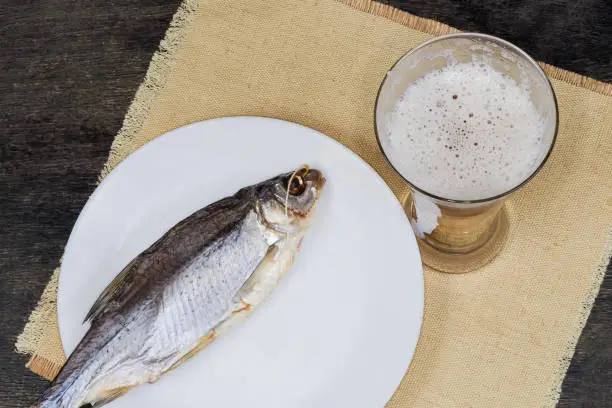 Photo of Top view of glass of beer against dried roach fish