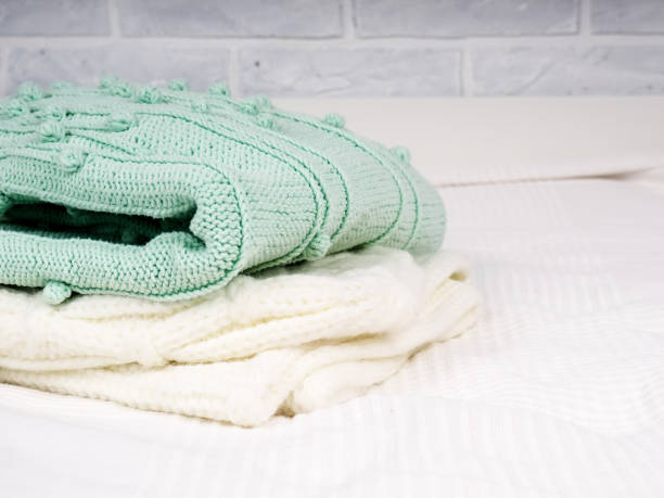 istock A stack of warm knitted things on a white bed. Cozy clothes. Household concept. folded knitted things white 1307178101
