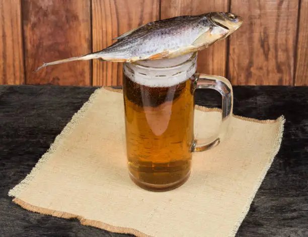 Photo of Salted dried roach fish on a lager beer glass